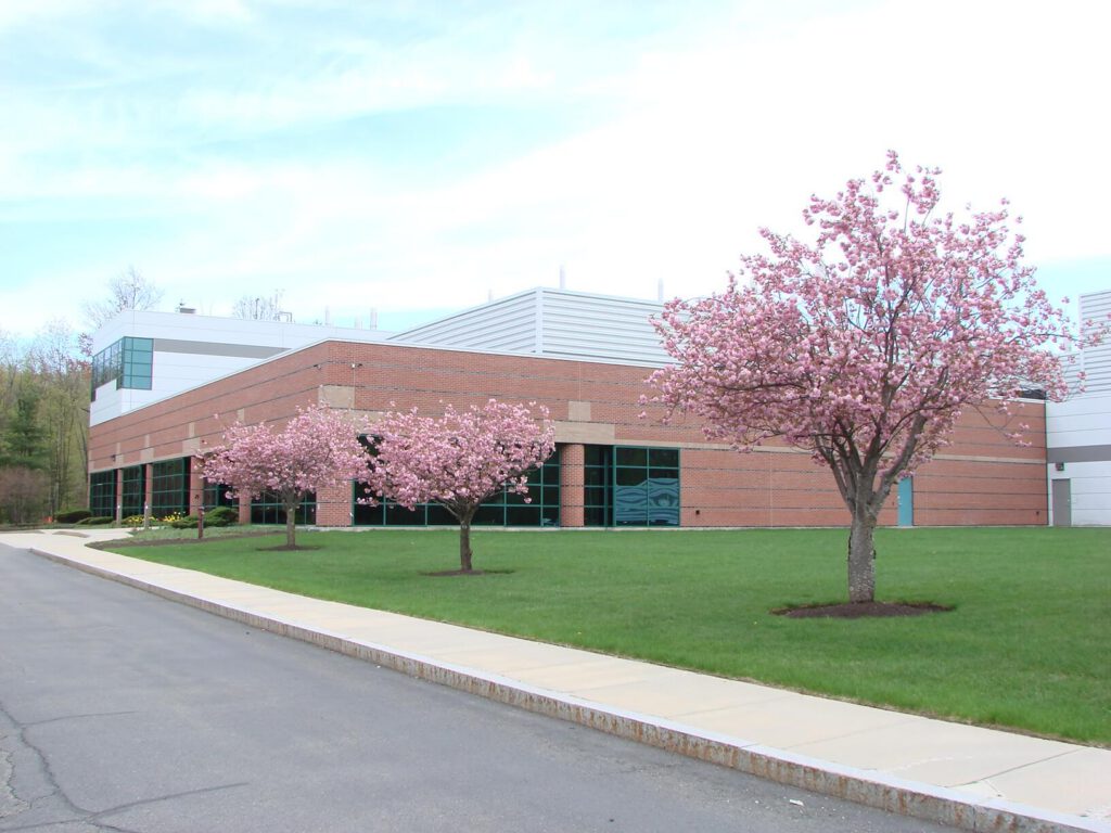 The Eisai Andover facility, a brick and glass building behind a lawn of flowering cherry trees